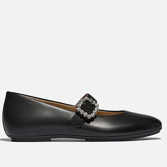 Black flat shoe with a decorative buckle on a light gray background