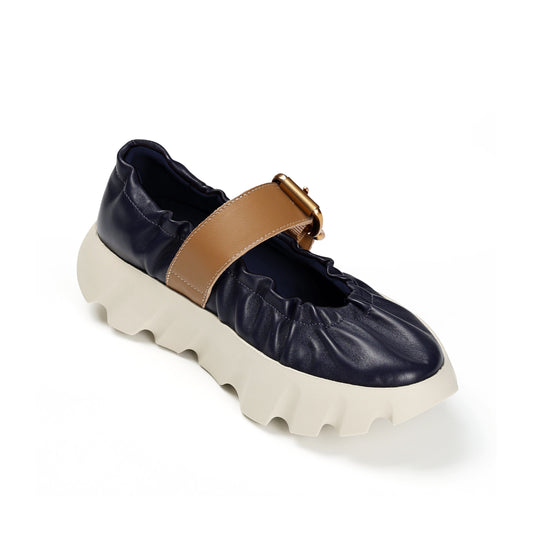 Navy shoe with tan strap and white sole on a white background